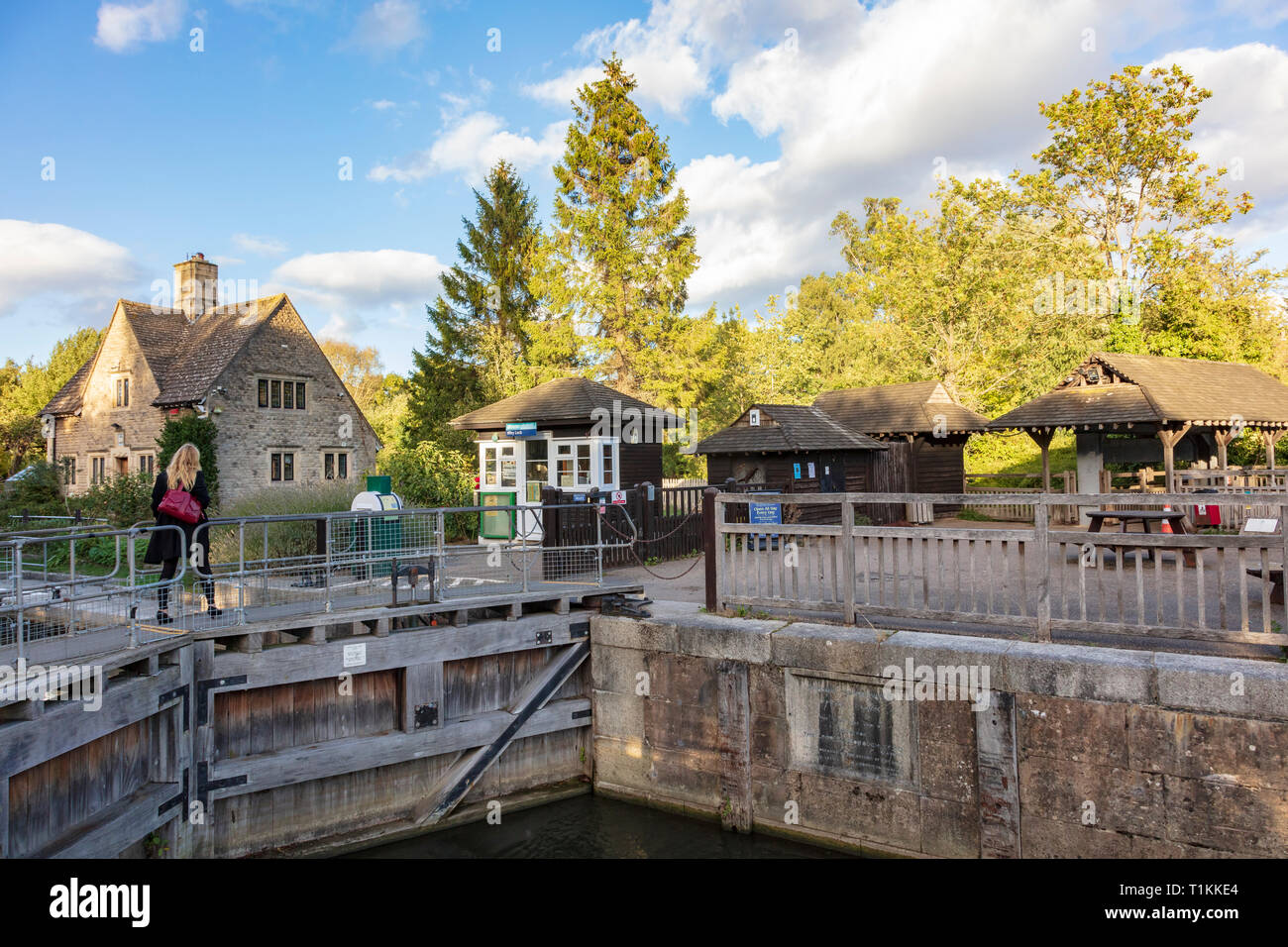 A blonde woman crosses the lock gates at Iffley Lock, Oxford, Oxfordshire, UK on the River Thames Stock Photo