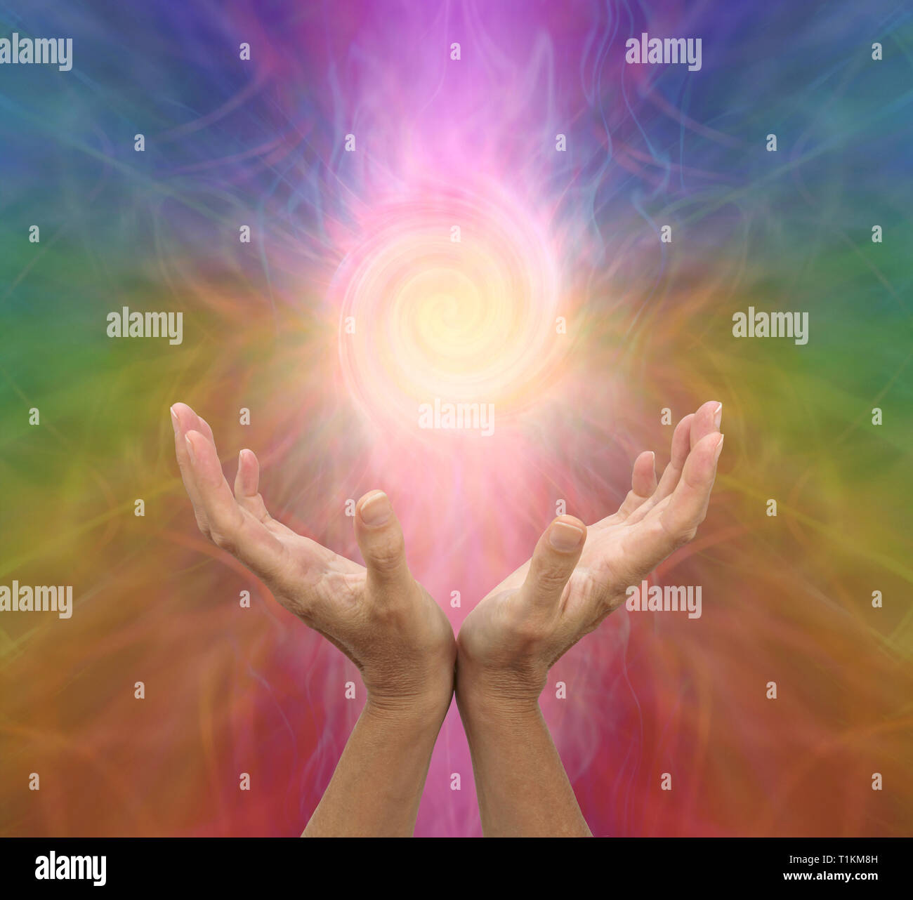 Channelling rainbow coloured vortex healing energy - female hands held open and palms upwards with a spiralling energy formation above Stock Photo