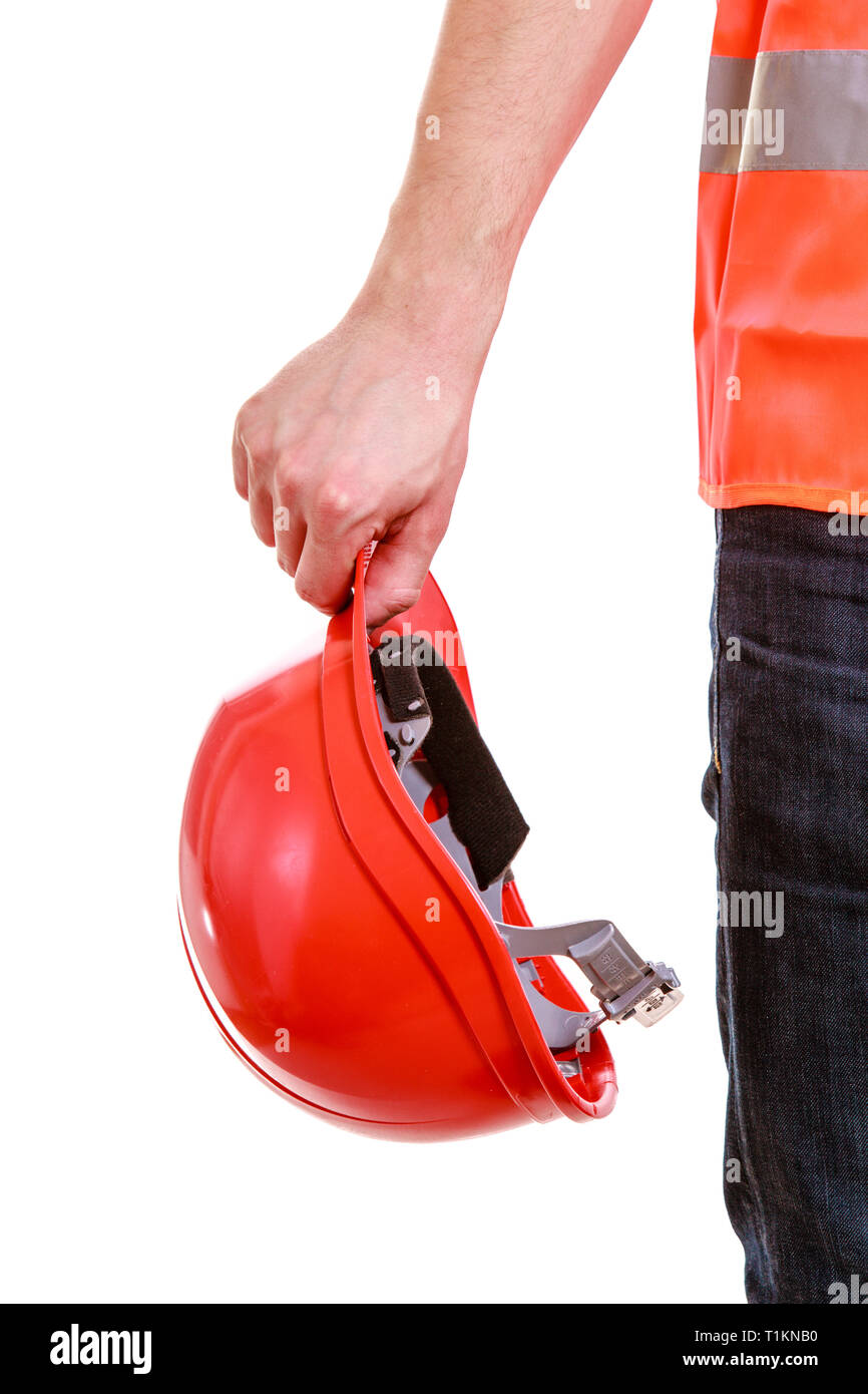 Red hard hat in hands of man construction worker builder foreman in orange safety vest isolated on white. Safety in industrial work. Studio shot. Stock Photo