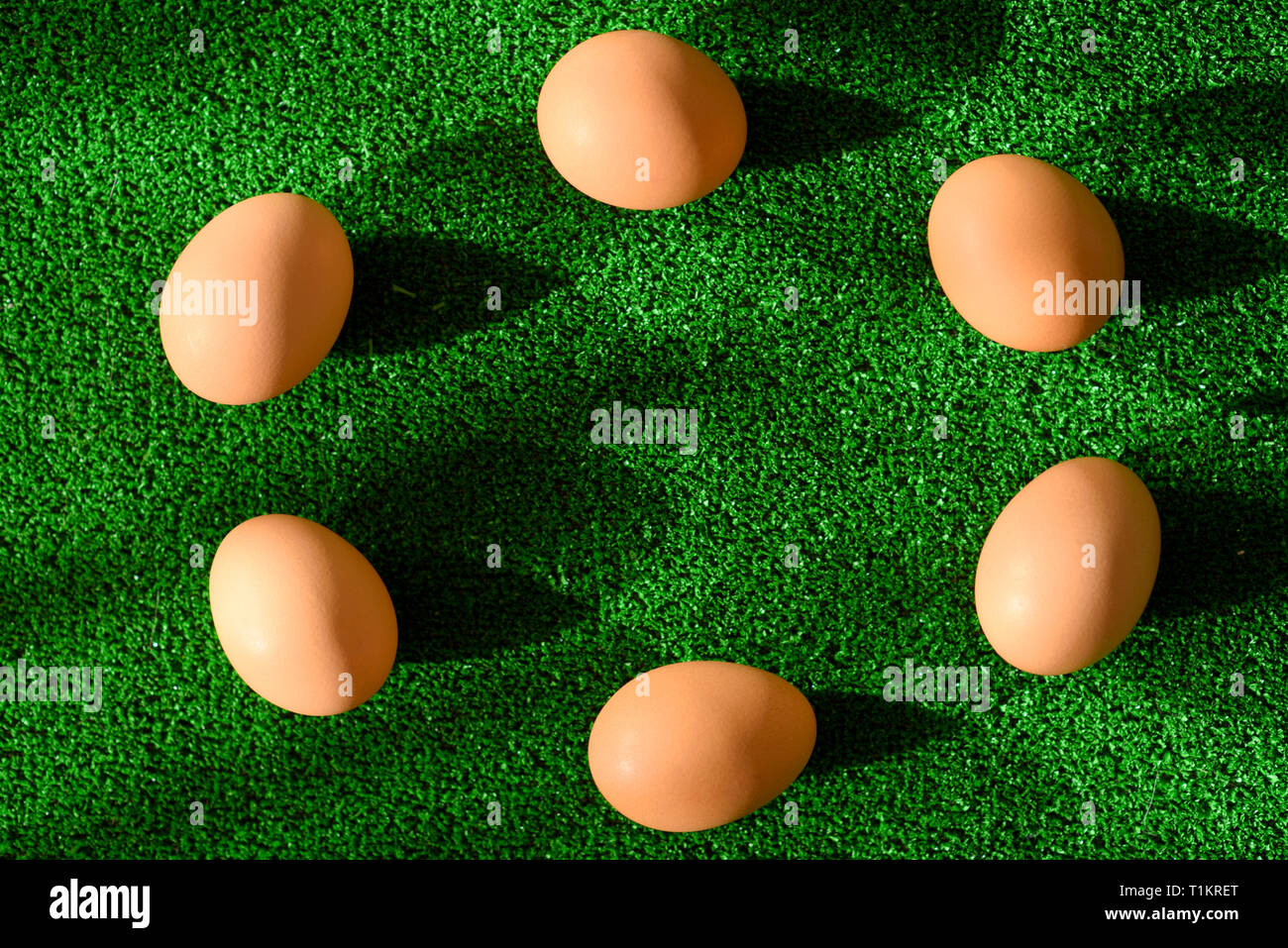 Top view of easter decoration - eggs arranged in a circle, on grass as a green background. Stock Photo
