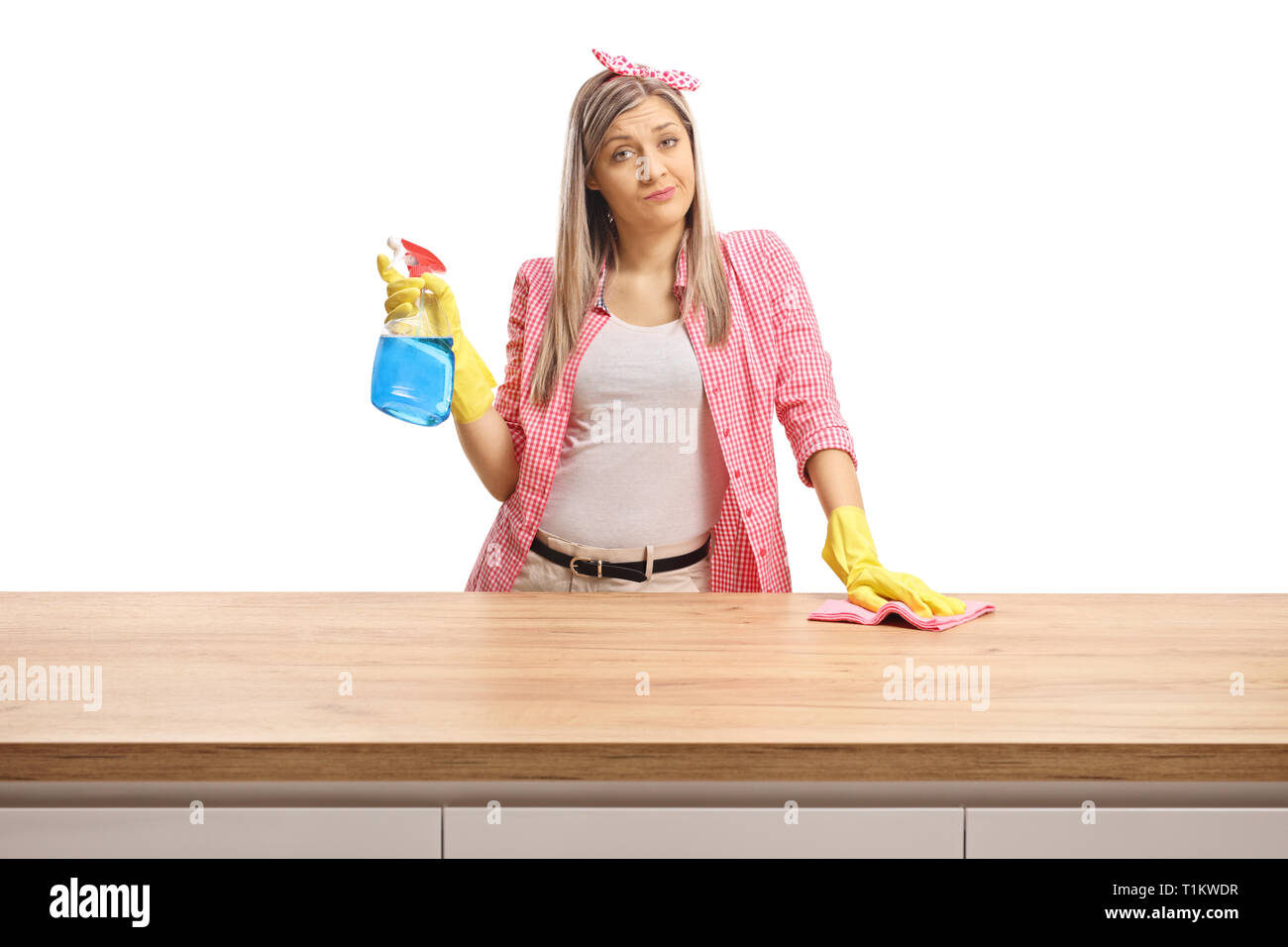Young woman behind a wooden counter fed up of cleaning isolated on white background Stock Photo