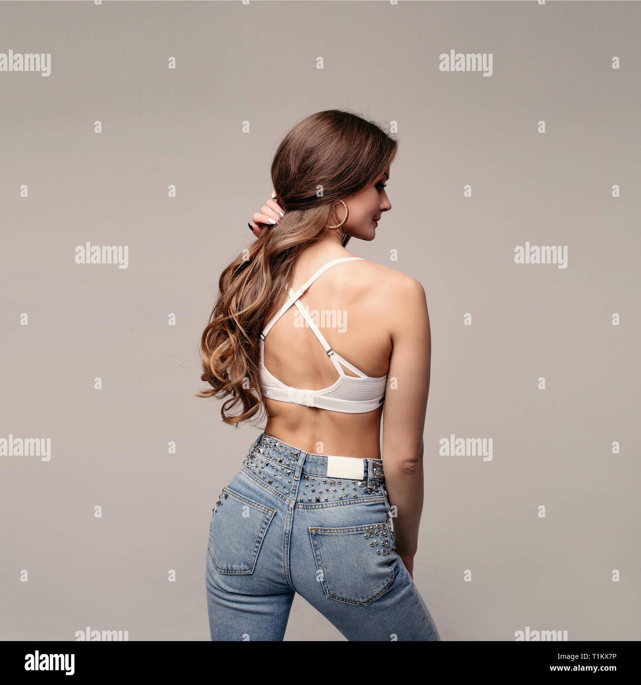 Brunette slim model in jeans and sports bra. Stock Photo by