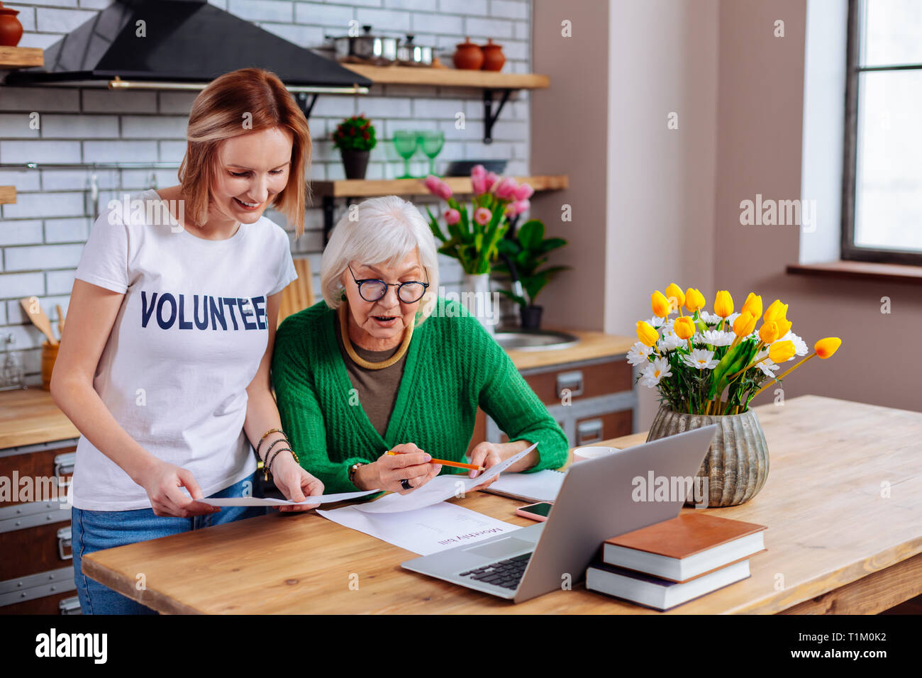 Charming Social Volunteer Showing Pensioner Loan Presentation On Laptop