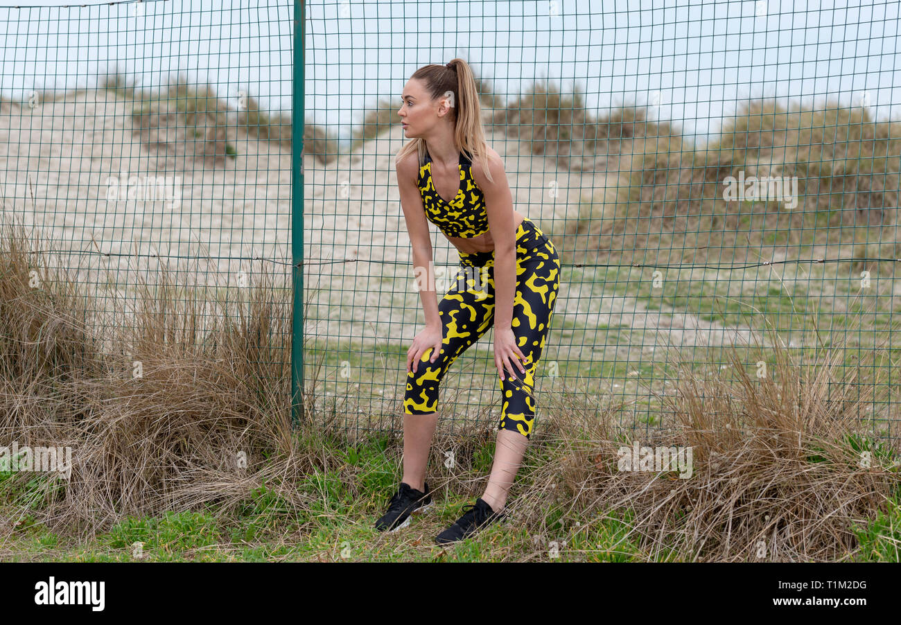 sporty woman resting with her hands on her kness catching her breath
