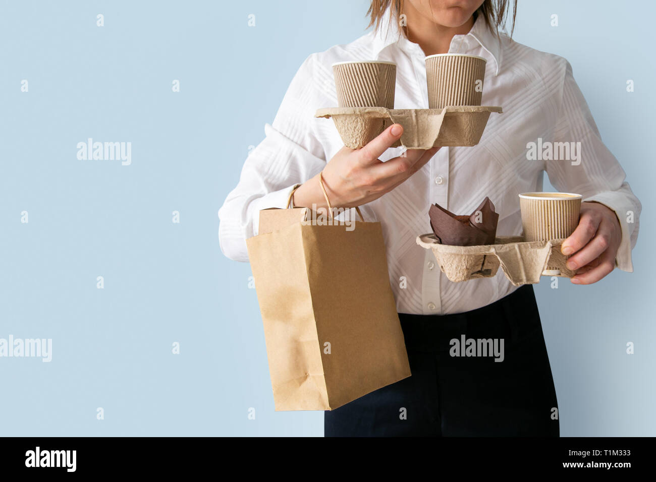 Female holding coffee containers, paper bag withfood containers. Food