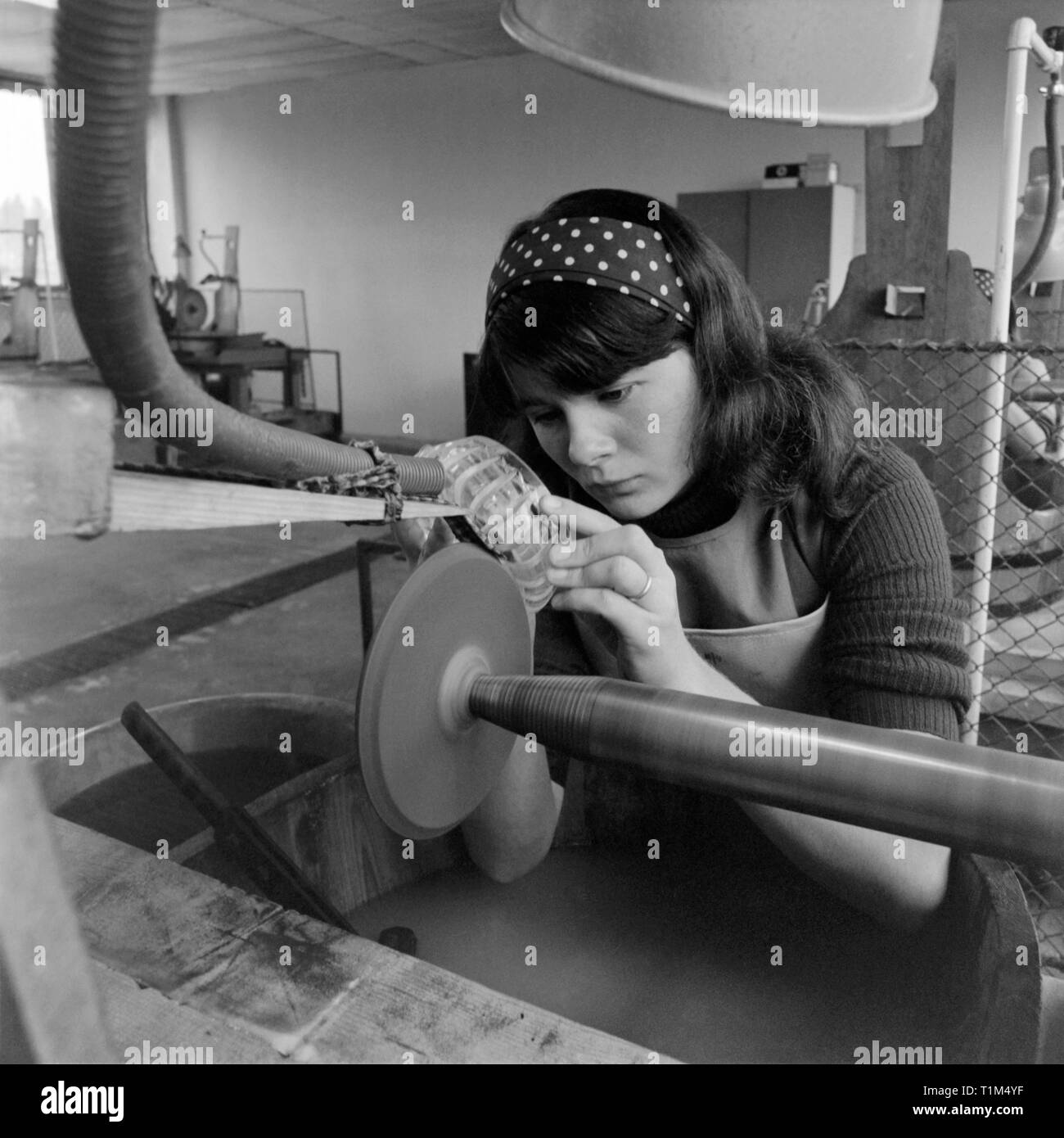 young female factory worker operating a machine to grind and polish glass 1970s hungary Stock Photo
