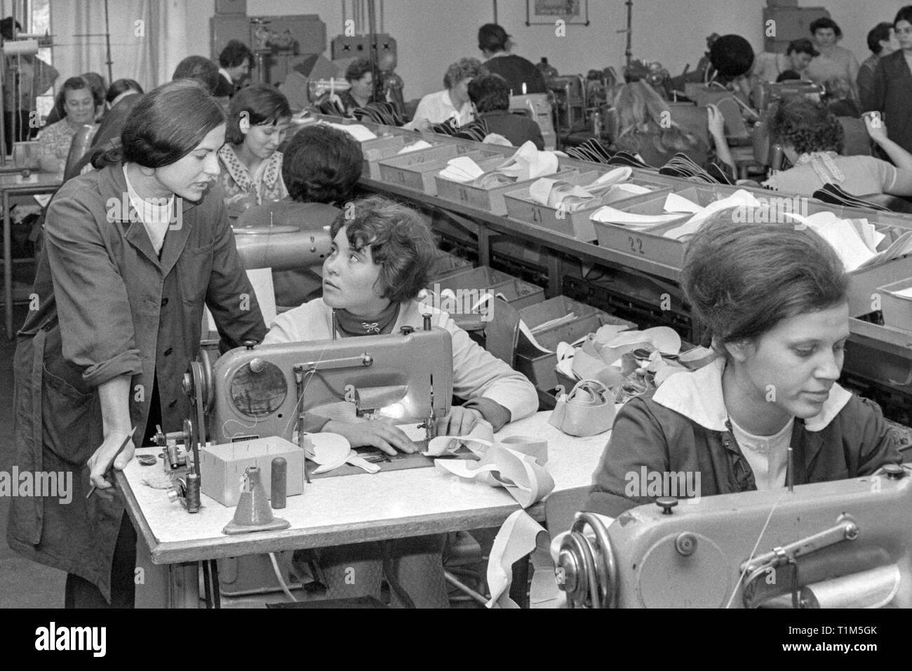female workers operate sewing machines in a busy factory 1960s hungary Stock Photo