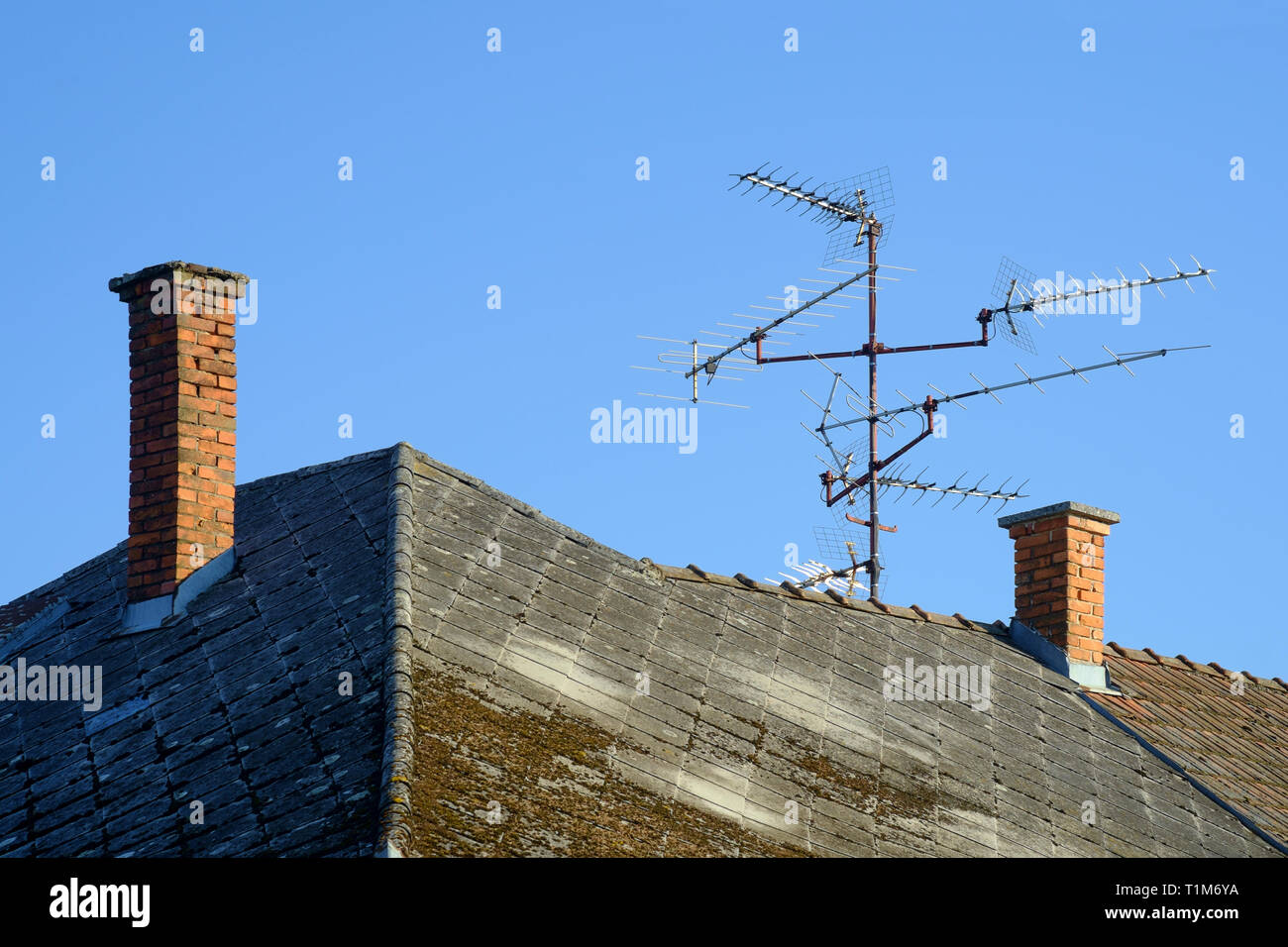 multiple narrow band uhf television aerials on a house roof in hungary Stock Photo
