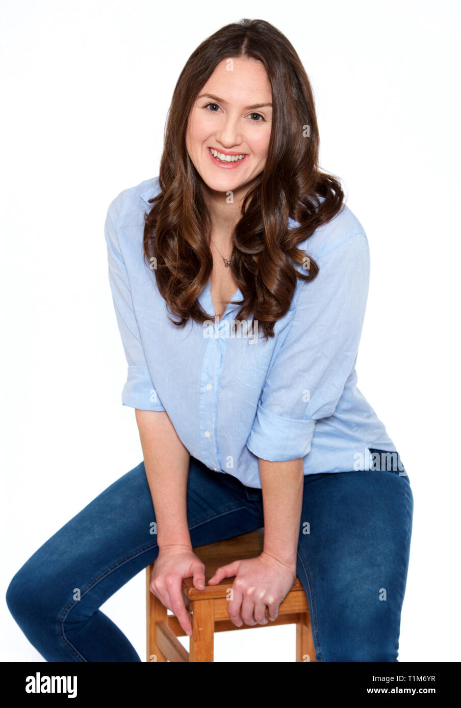 Happy woman in her thirties, sitting on stool Stock Photo