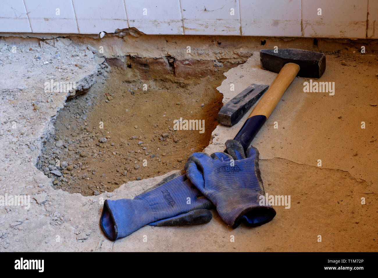 hammer chisel and protective gloves being used to dig out an old concrete floor in a rural house in hungary Stock Photo