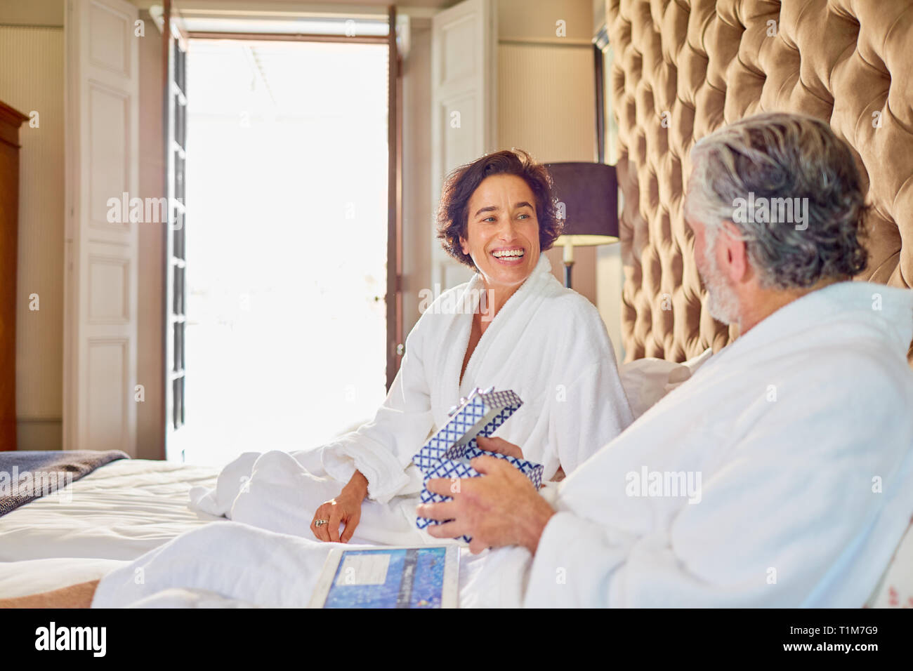 Happy mature couple in bathrobes on bed Stock Photo