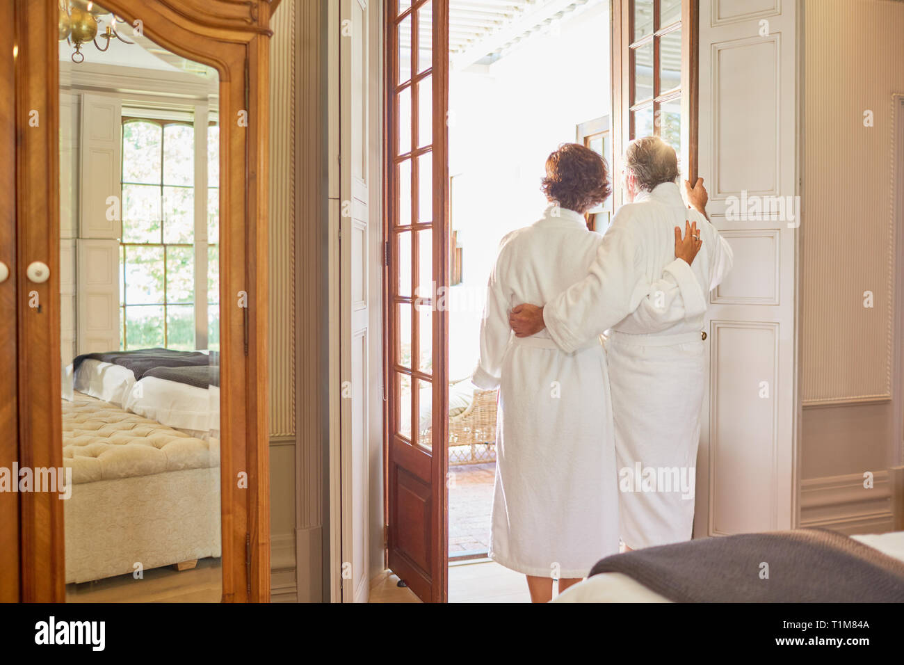 Mature couple in spa bathrobes standing at hotel balcony doorway Stock Photo