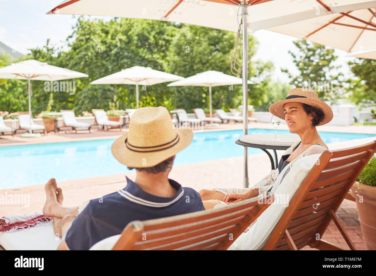 Couple relaxing on lounge chairs at resort poolside Stock Photo