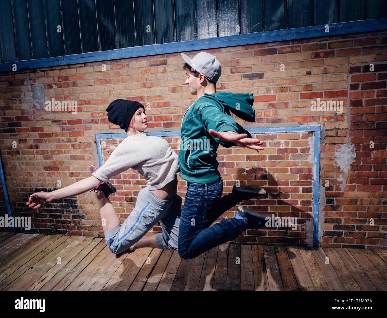 Modern dancers performing against brick wall Stock Photo