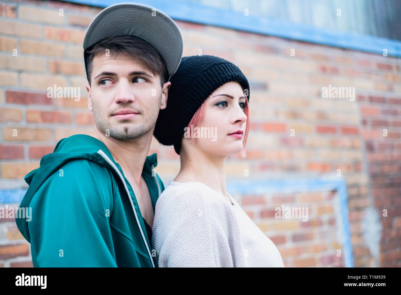 Young couple standing against brick wall Stock Photo