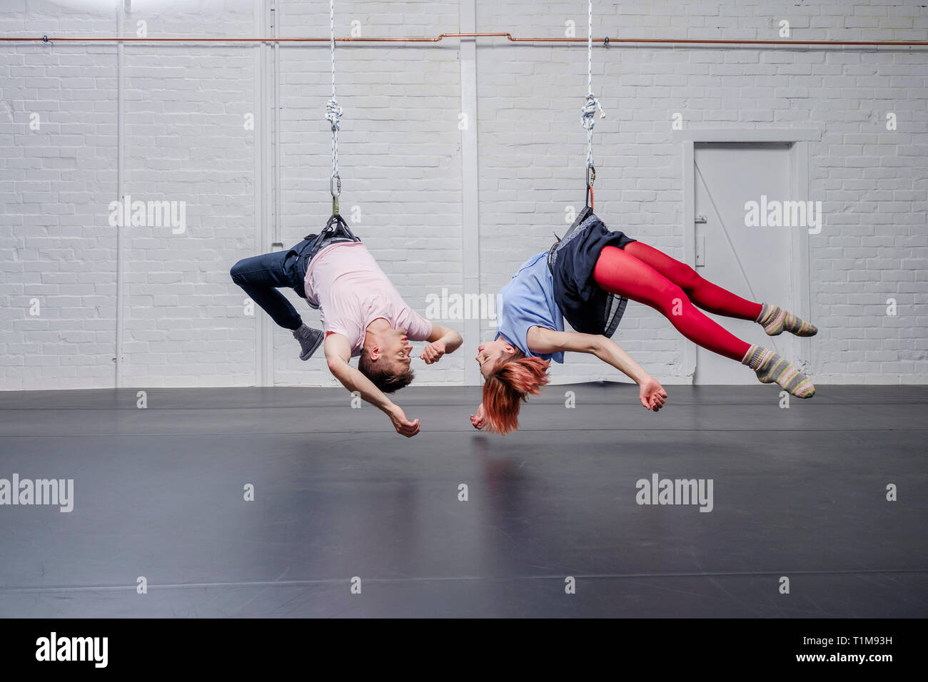 Modern aerialist dancers performing, hanging upside-down Stock Photo