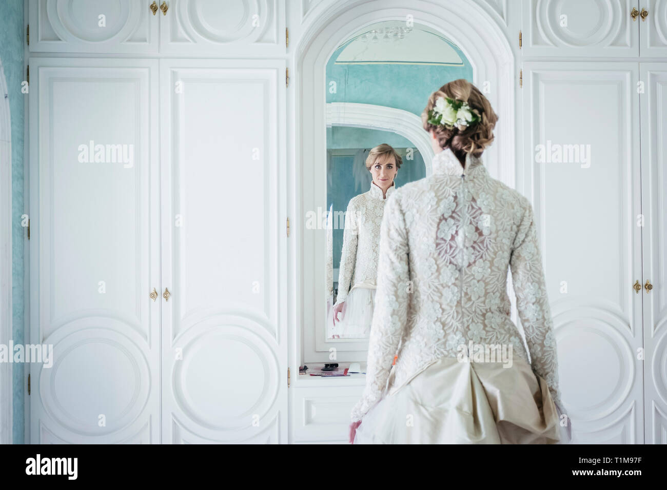Elegant bride in lace wedding dress at mirror Stock Photo