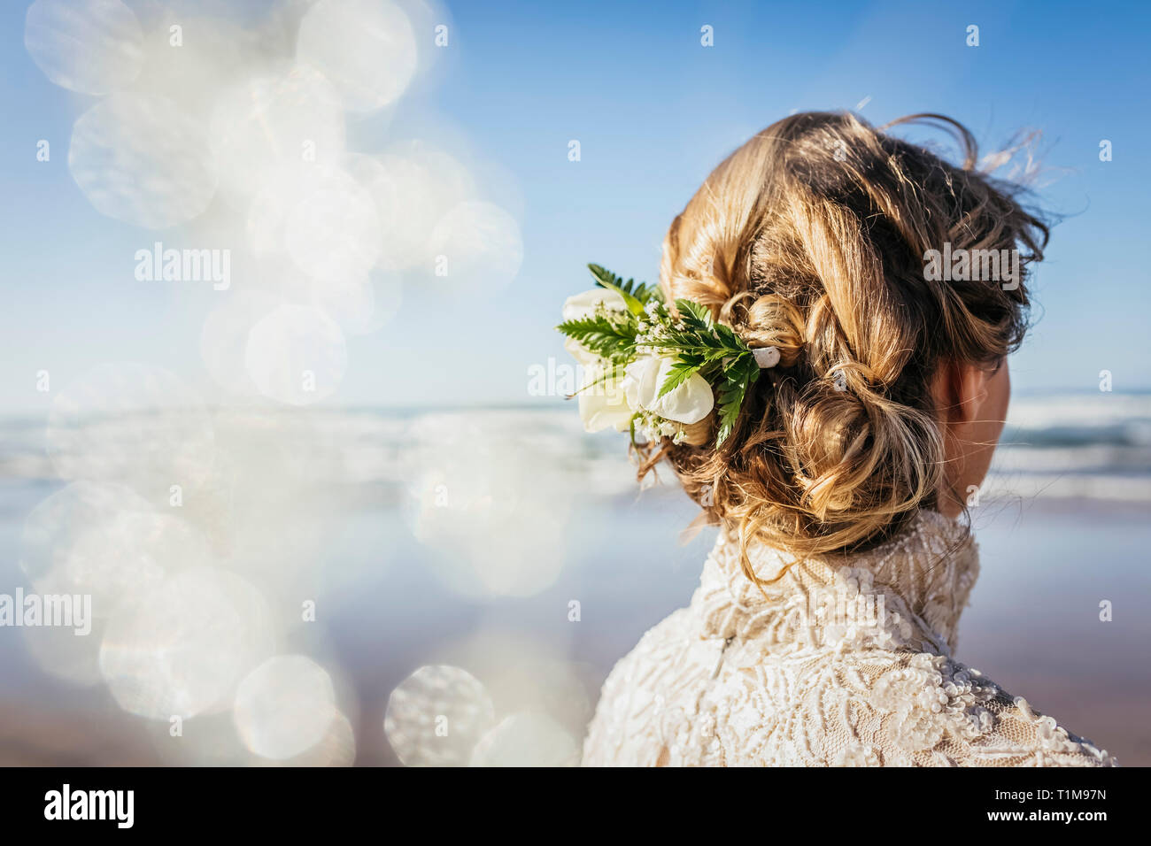 Blonde bride with flowers in hair on sunny beach Stock Photo