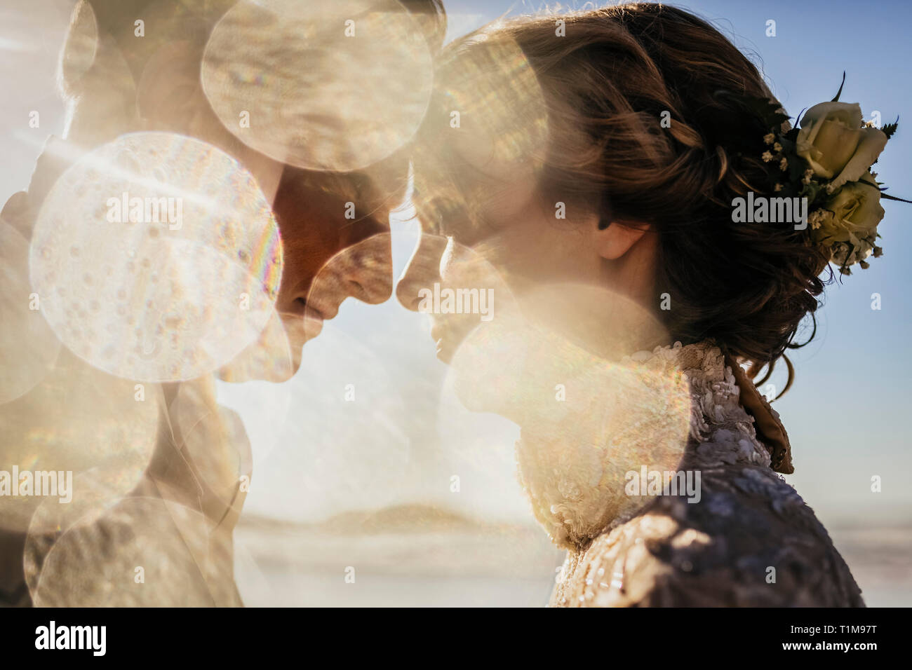 Golden light illuminating profile of bride and groom Stock Photo
