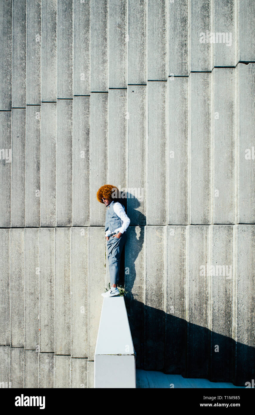 View from above young man with afro laying on sunny urban steps Stock Photo