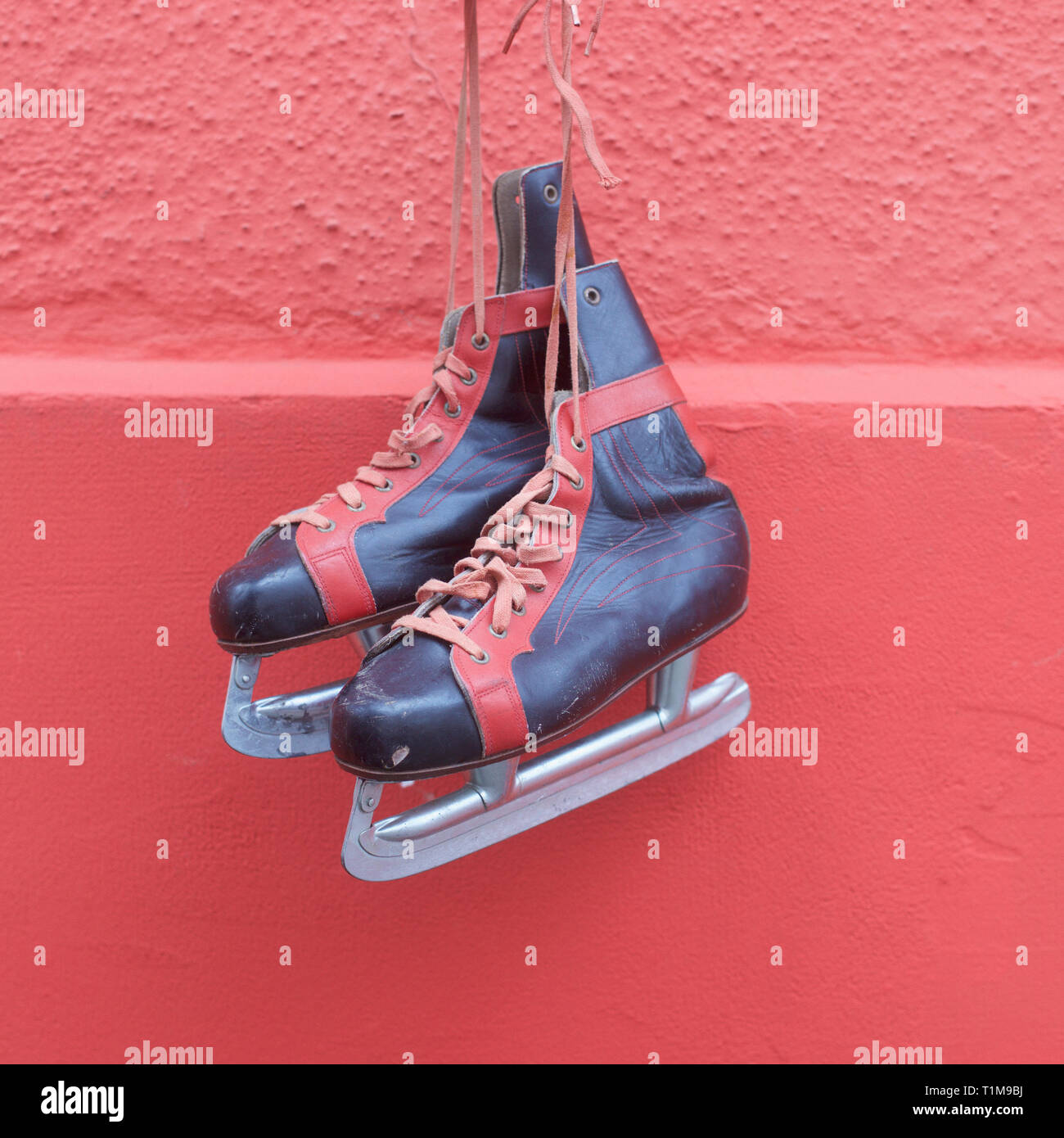 Ice skates hanging against red wall Stock Photo