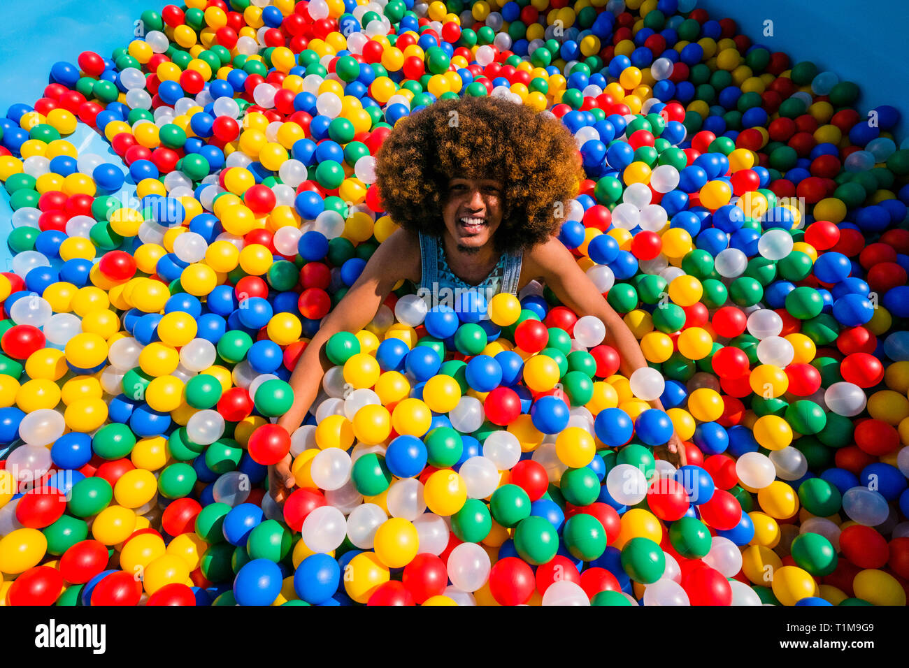 Portrait exuberant young man playing in multicolor ball pool Stock Photo