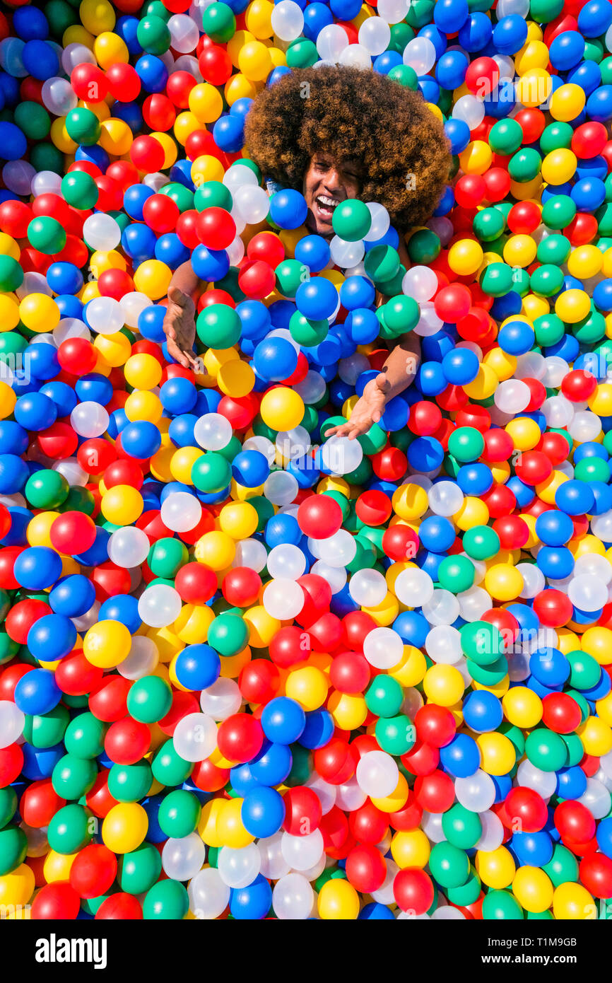 Portrait playful young man in multicolor ball pool Stock Photo