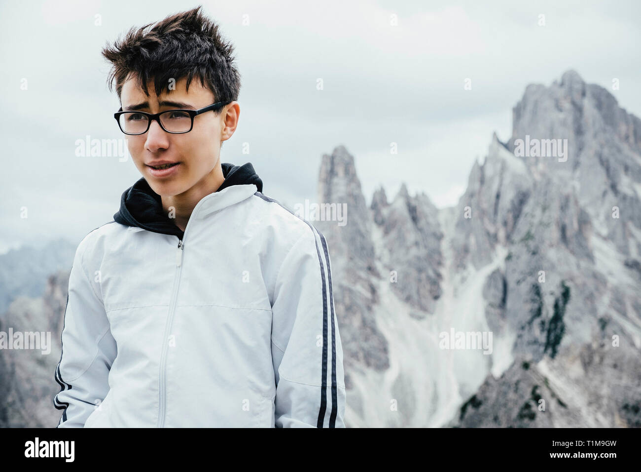 Teenage boy standing at rugged mountain peaks, Drei Zinnen Nature Park, South Tyrol, Italy Stock Photo