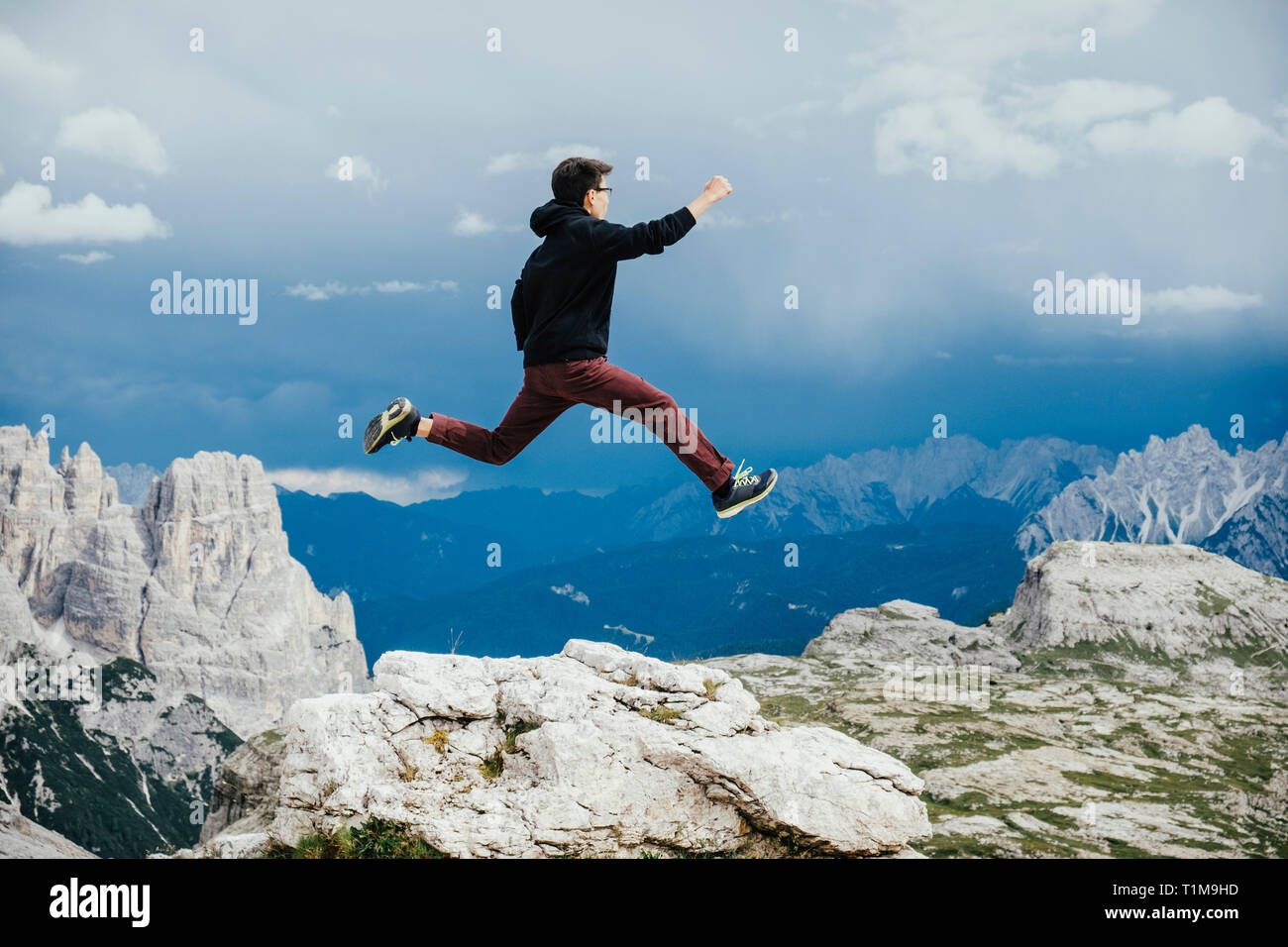 Carefree boy jumping over rocks on mountain, Drei Zinnen Nature Park, South Tyrol, Italy Stock Photo
