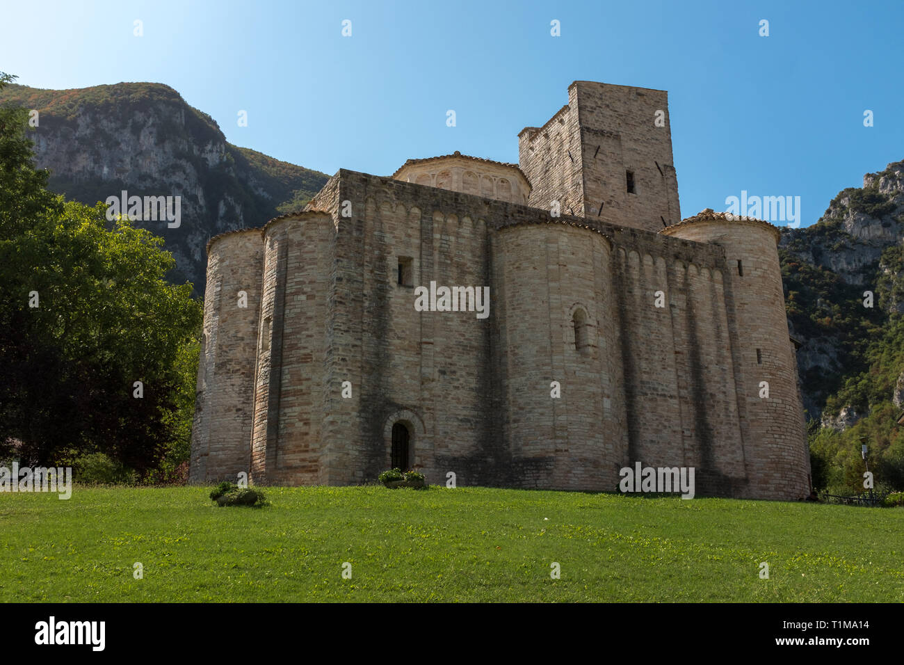 The stunning San Vittore alle Chiuse with it's round towers is a Roman Catholic abbey and church in the comune of Genga, Marche, Italy against a brigh Stock Photo