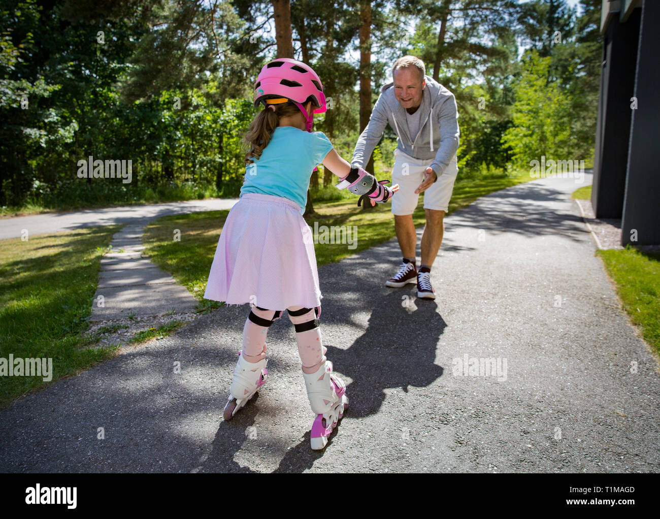 Father teaching his daughter to skate on roller skates. Happy kid in helmet  learning skating. Family spending time together. Sunny summer day on subur  Stock Photo - Alamy