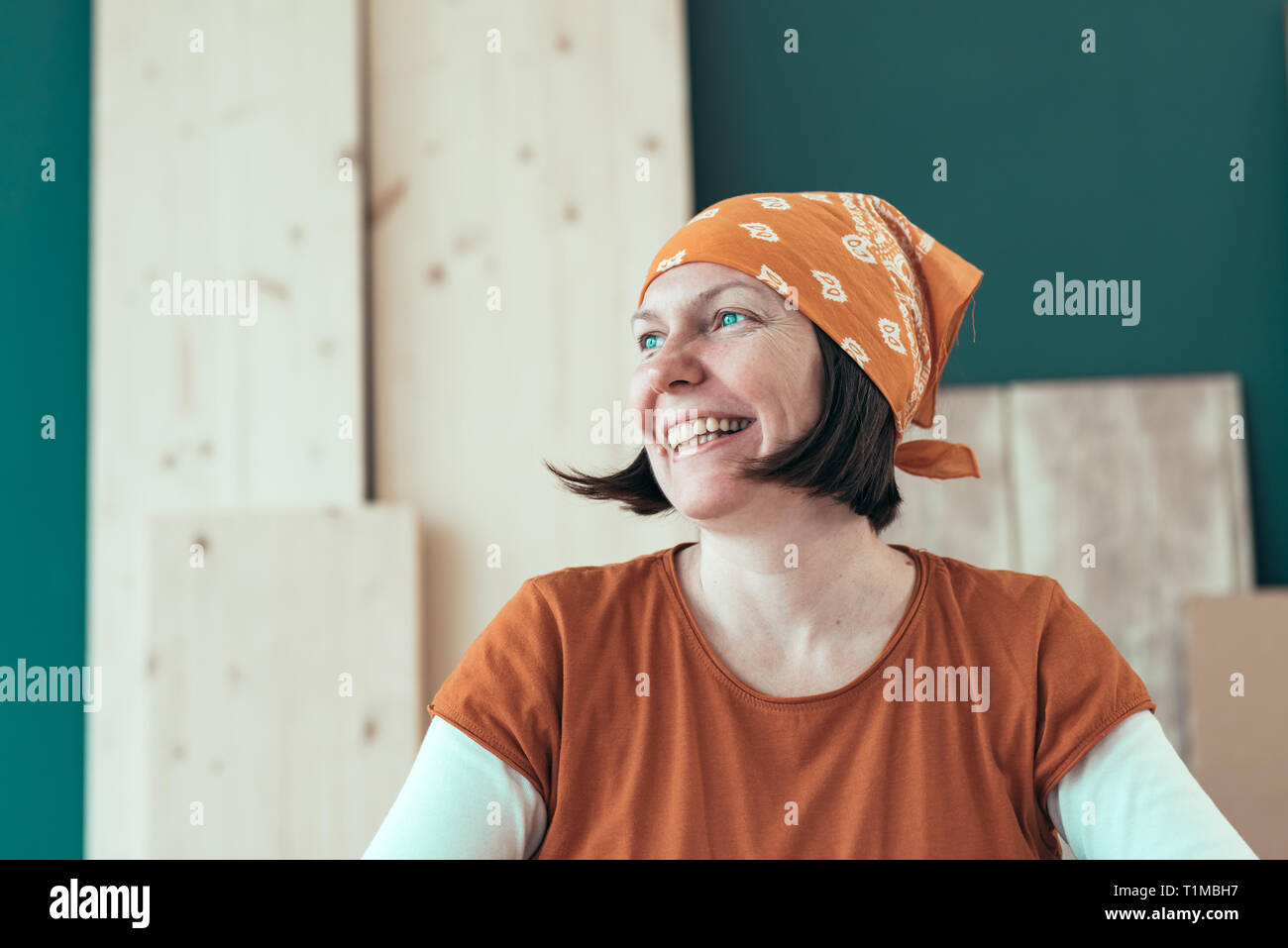 Portrait of smiling happy female carpenter wearing headscarf bandana in small business woodwork workshop Stock Photo