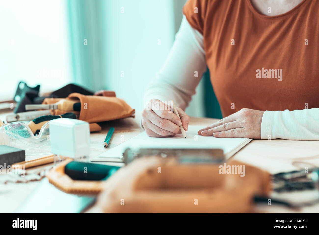 Self employed female carpenter writing project notes on clipboard note paper, selective focus Stock Photo