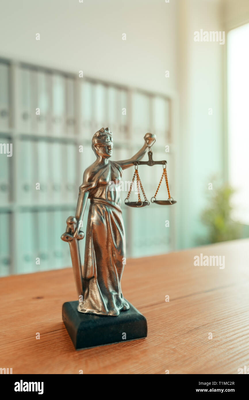 Lady Justice statue in law firm attorney office, blindfolded Justitia with balance scales and sword is personification of moral force in judicial syst Stock Photo