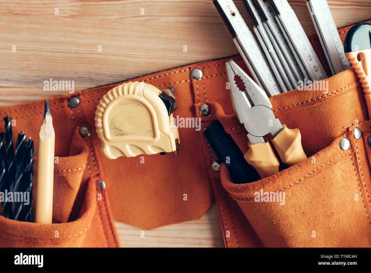 Female carpenter organizing tool belt set in woodwork workshop, close up Stock Photo