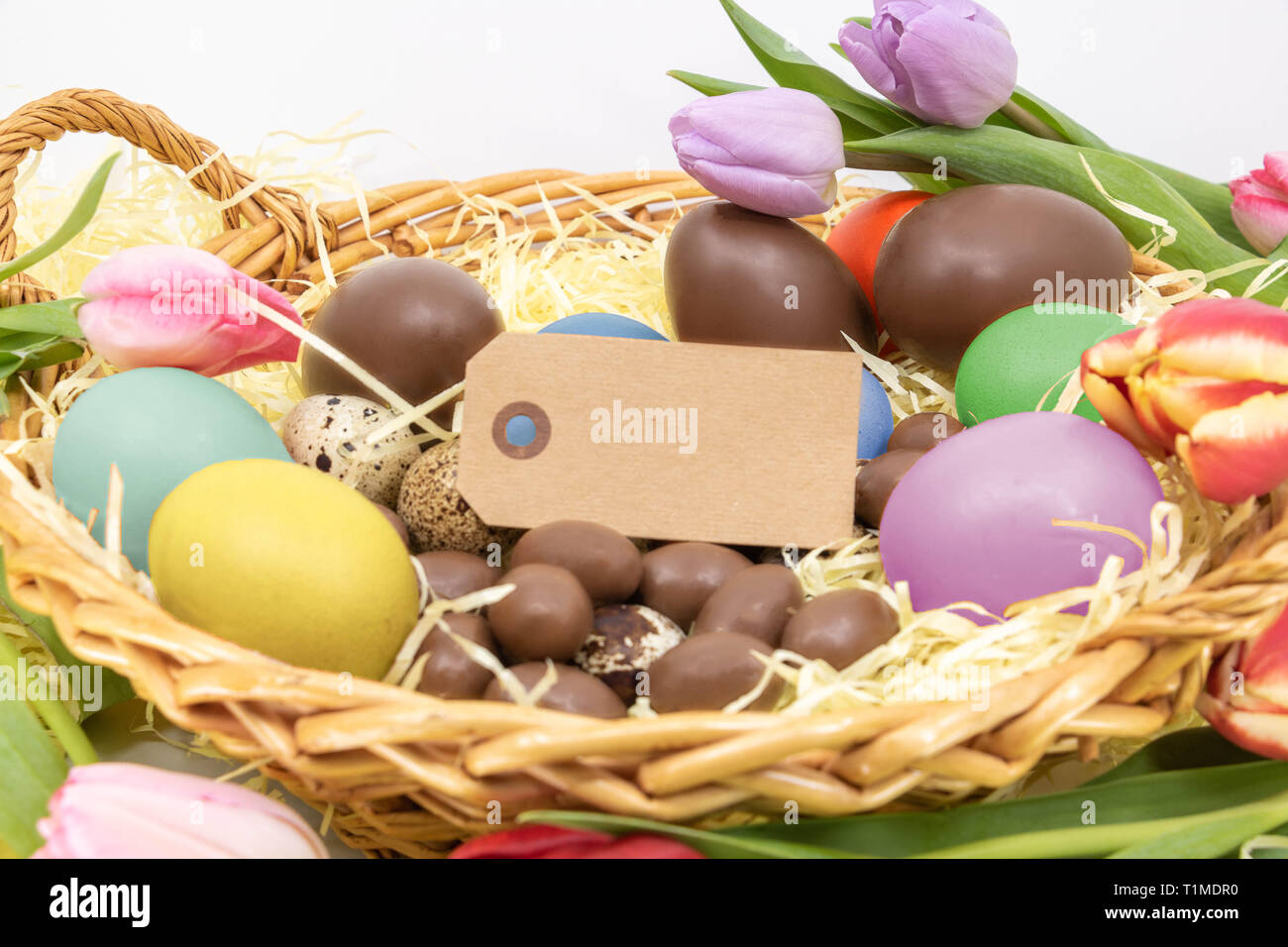 Text box on label surrounded by chocolate Easter eggs, quail egg and painted chicken eggs Stock Photo