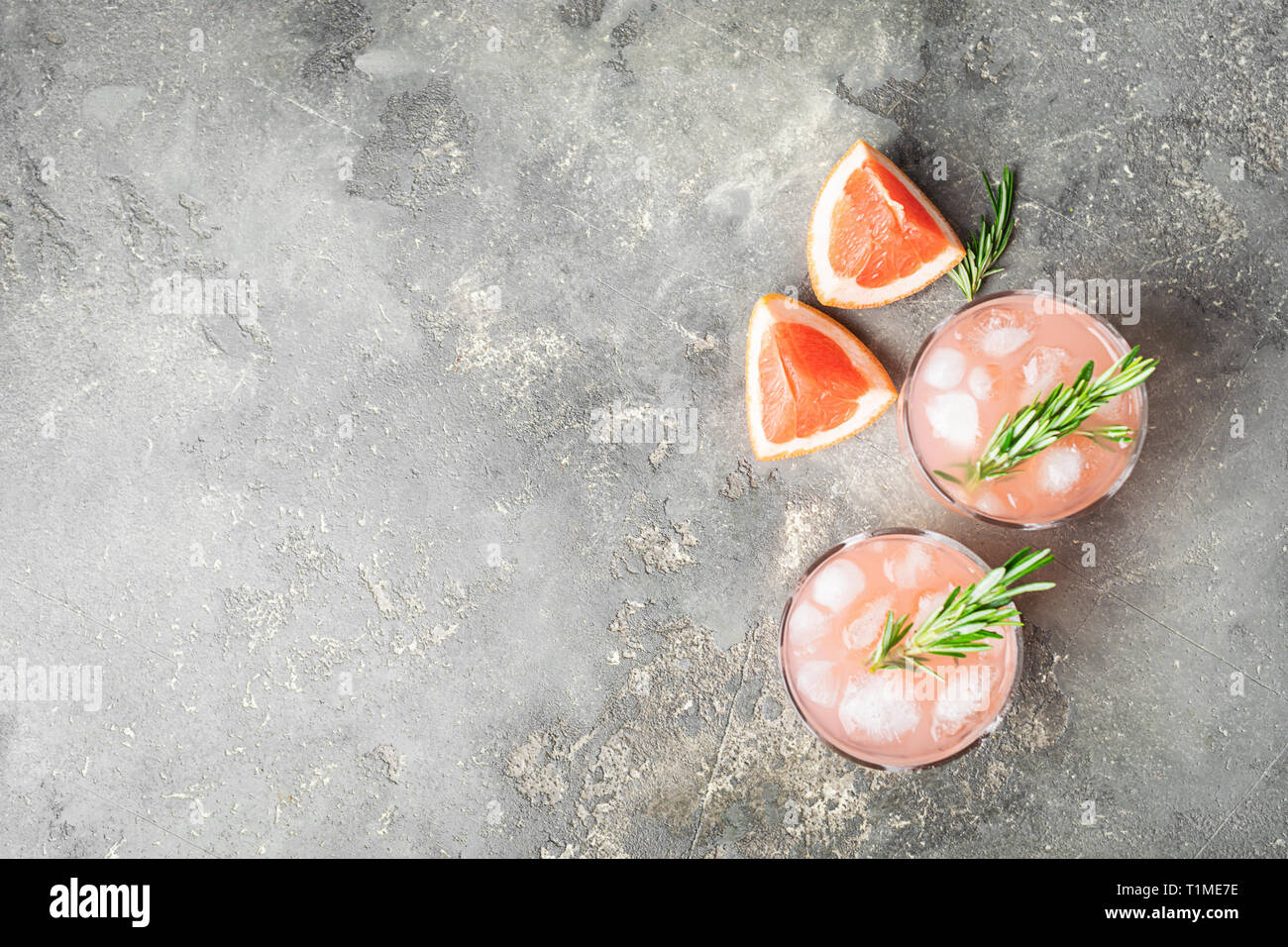 Refreshing summer cocktail grapefruit champagne rosemary juice in two glass goblets on a light gray concrete background. Stock Photo