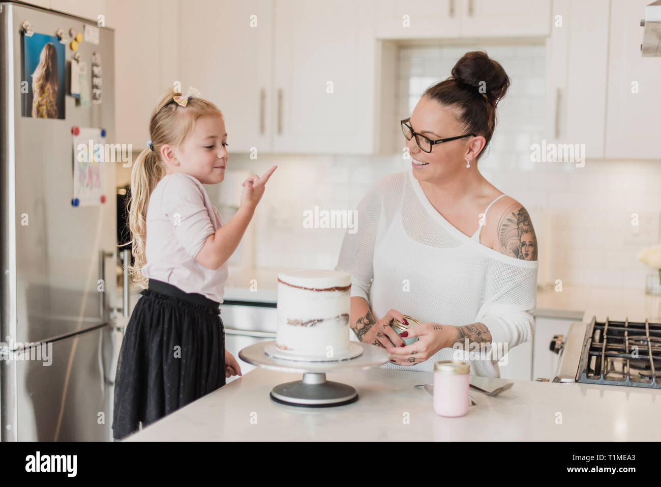 Mother and daughter decorating cake in kitchen Stock Photo