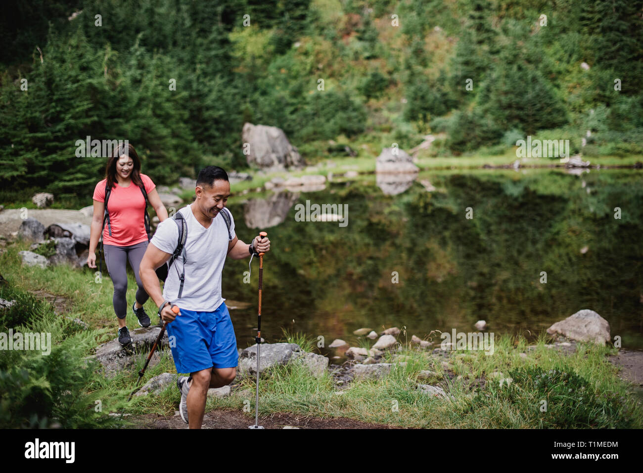 Couple hiking along lake in woods Stock Photo