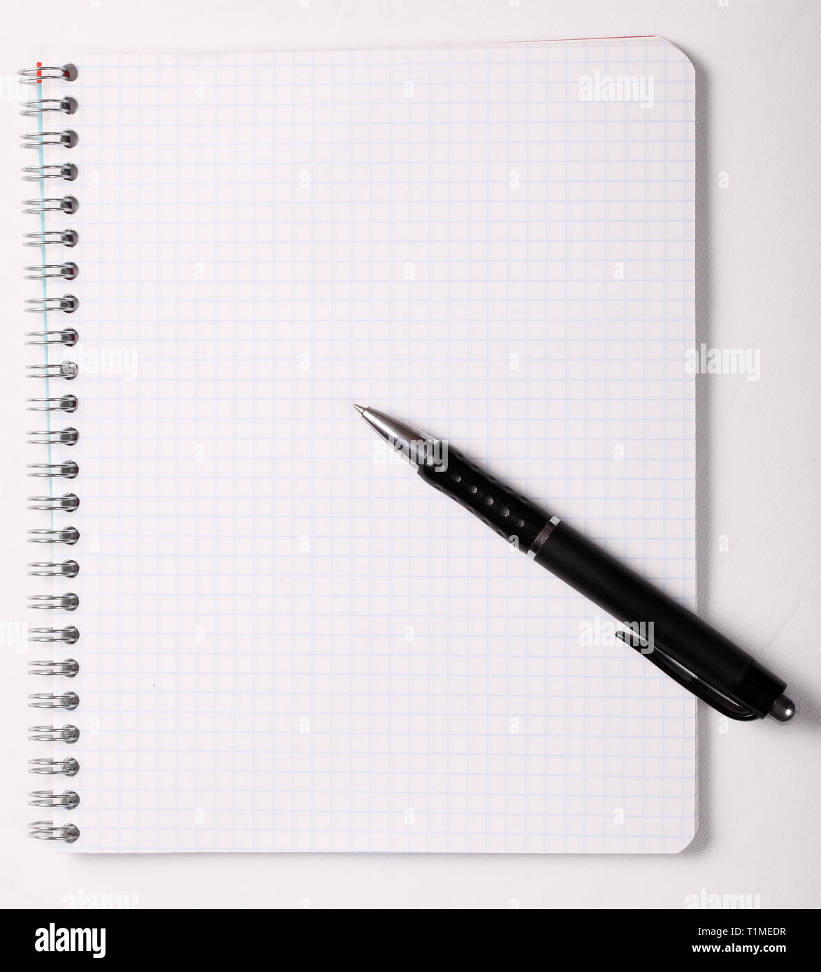 Checked notebook and black pen on white background Stock Photo