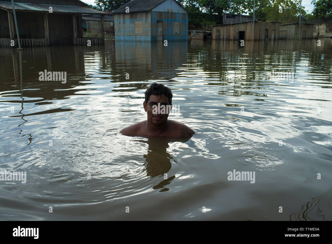 2015 flooding in Brazilian Amazon - flooded houses in Taquari district, Rio Branco city, Acre State. Jose Alcides dos Santos swims in the dark and dirt waters of Acre river. Floods have been affecting thousands of people in the state of Acre, northern Brazil, since 23 February 2015, when some of the state’s rivers, in particular the Acre river, overflowed. Further heavy rainfall has forced river levels higher still, and on 03 March 2015 Brazil’s federal government declared a state of emergency in Acre State, where current flood situation has been described as the worst in 132 years. Stock Photo