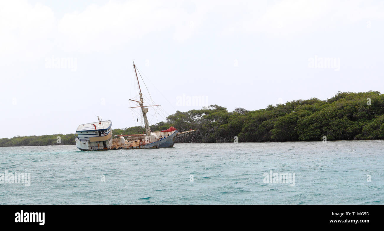 An abandoned ship lists to the starboard side in the shallow waters near Renaissance Island, Aruba. Stock Photo
