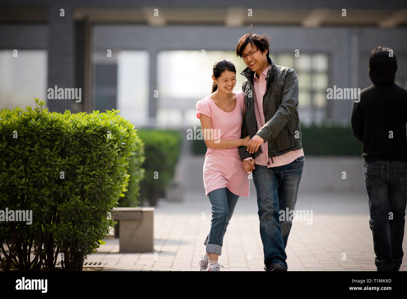 Young couple holding hands walking through a park. Stock Photo