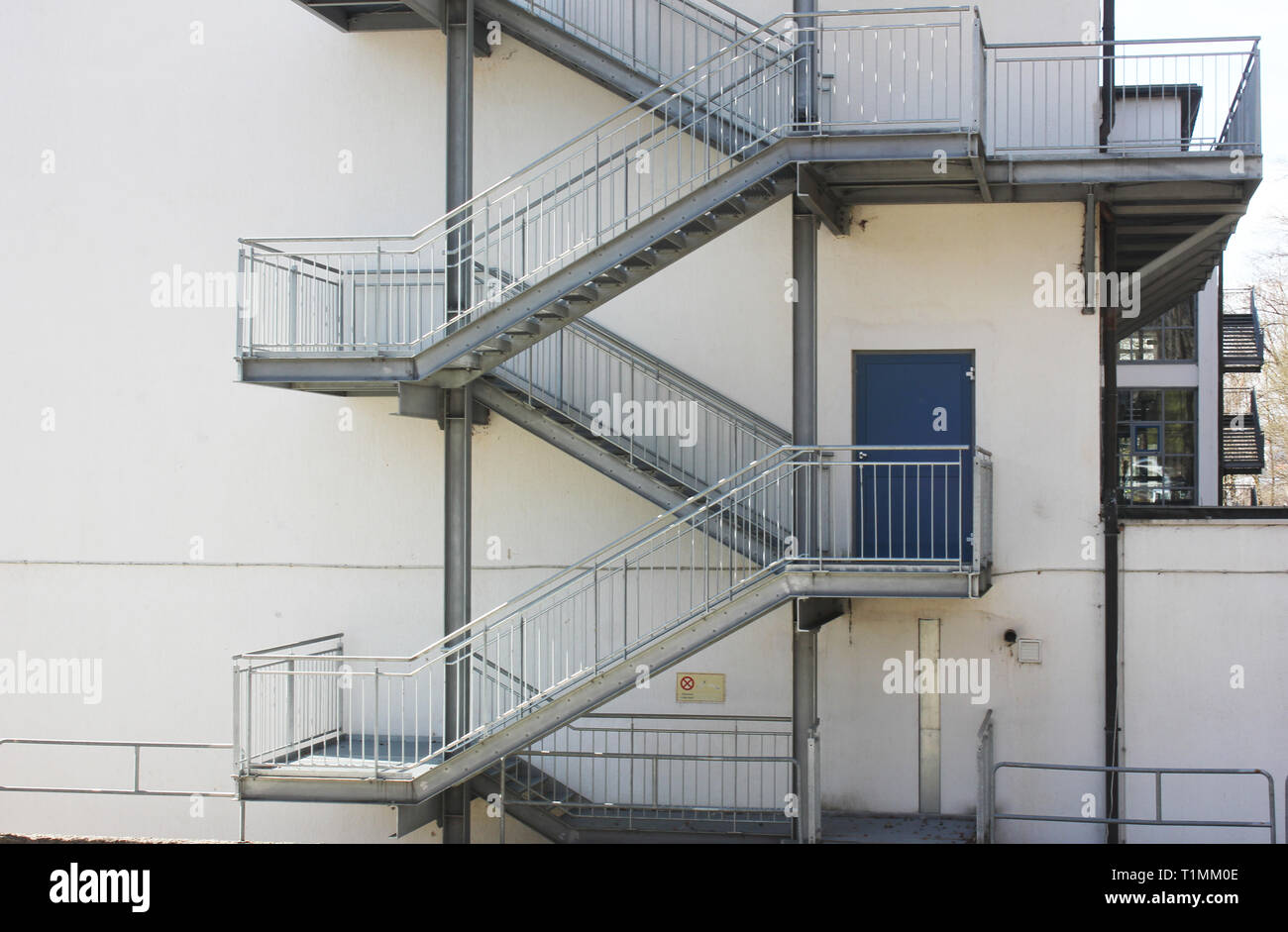 Fire exit staircase in front of white housewall. Stock Photo