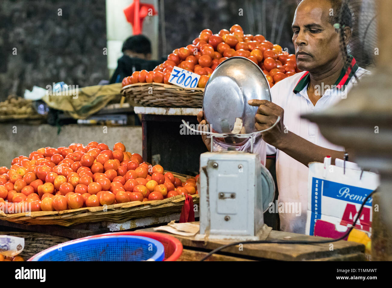 Port Louis, Mauritius - January 29, 2019: A vegetables vendor putting tomatoes inside a bag for a customer at the Central Market in Port Louis, Maurit Stock Photo