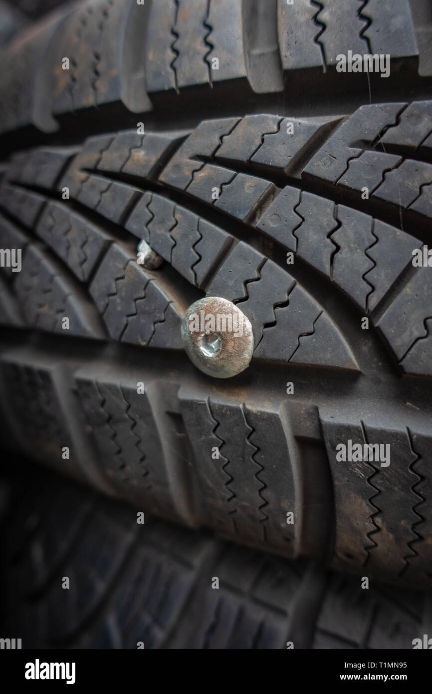 Closeup of a used and useless car tyre pierced with a metal rivet Stock Photo
