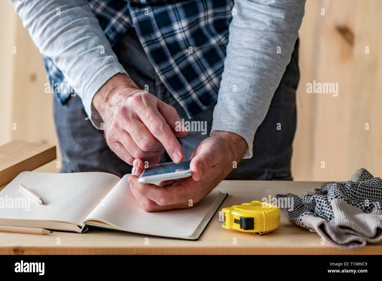 Carpenter making project calculation using smartphone app in small business woodwork workshop Stock Photo