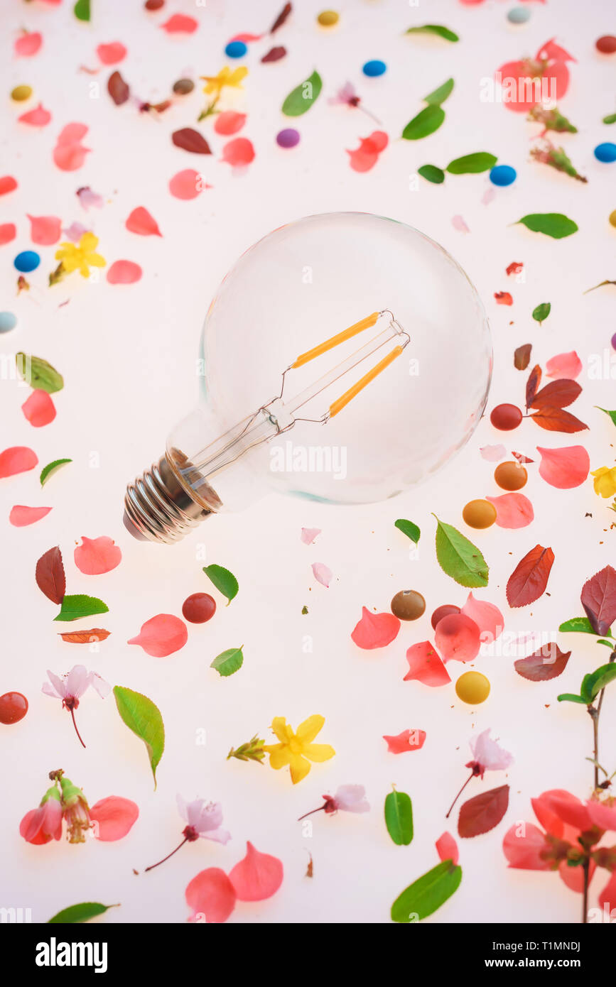 Light bulb creativity and new ideas concept over the springtime floral arrangement of colorful petals and leaves Stock Photo