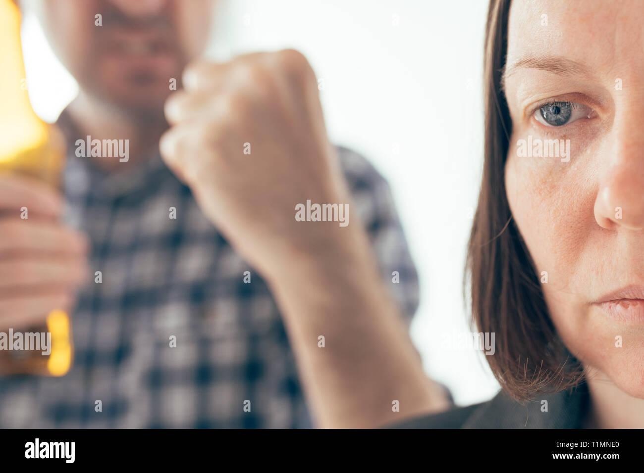 Drunk man drinking beer and arguing with his wife at home, adult caucasian couple in domestic dispute concept yelling at each other. Stock Photo