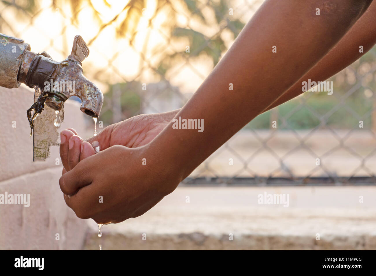Closeup of hands, child drinking water directly from corporation tap water in India. Stock Photo